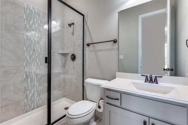 bathroom with toilet, a textured wall, a shower stall, and vanity