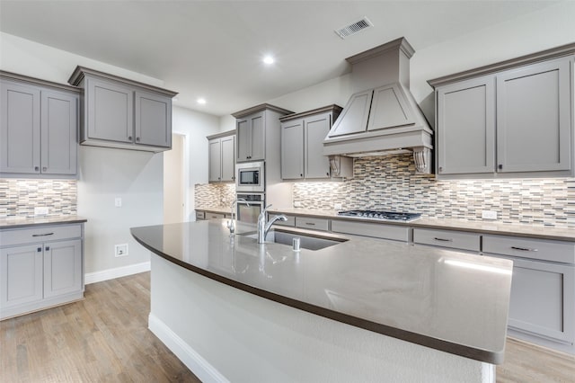 kitchen with custom exhaust hood, gray cabinets, visible vents, appliances with stainless steel finishes, and a sink