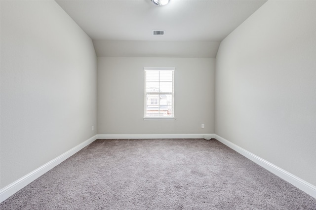 carpeted empty room featuring visible vents, baseboards, and vaulted ceiling