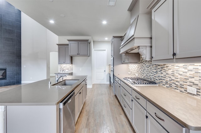 kitchen featuring stainless steel appliances, visible vents, gray cabinetry, a sink, and light wood-type flooring