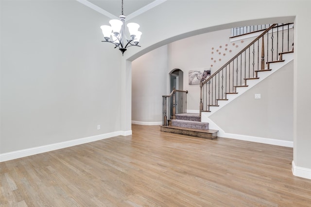 foyer featuring arched walkways, crown molding, baseboards, and wood finished floors