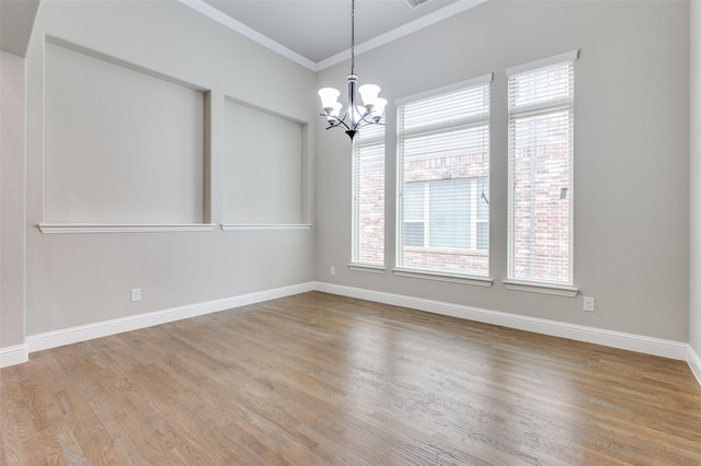 empty room featuring light wood-type flooring, baseboards, ornamental molding, and a notable chandelier