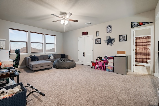 carpeted living room featuring visible vents, ceiling fan, and baseboards