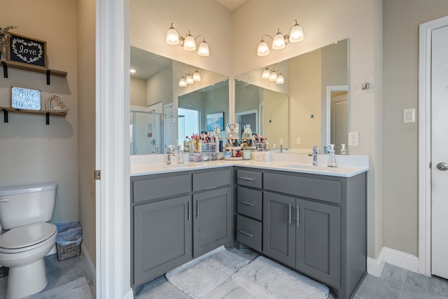 full bath featuring double vanity, toilet, a sink, a shower stall, and baseboards