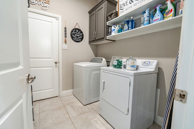 washroom with cabinet space, baseboards, and separate washer and dryer