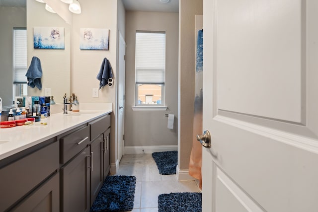 full bath with tile patterned flooring, a sink, baseboards, and double vanity