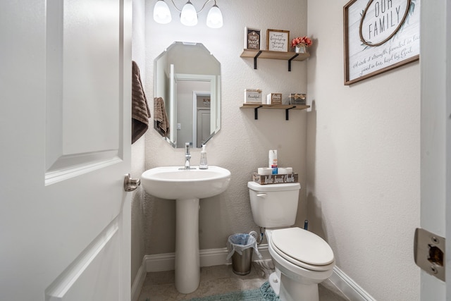 half bath featuring baseboards, a sink, toilet, and tile patterned floors