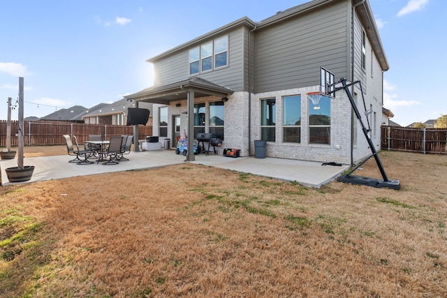 back of property with a patio area, a fenced backyard, a lawn, and brick siding