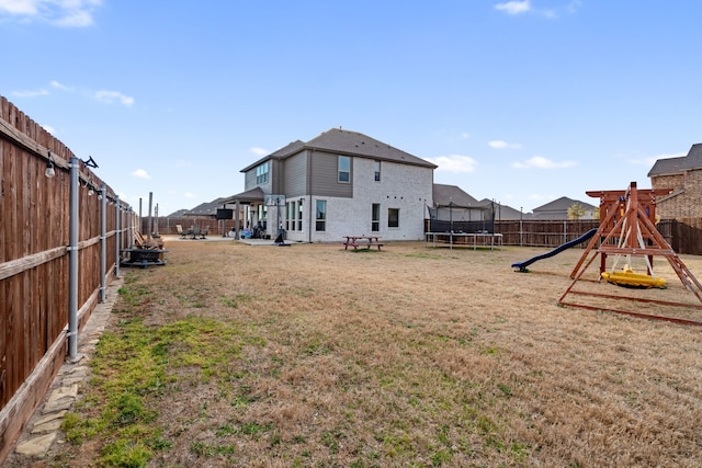 view of yard featuring a trampoline, a playground, a patio, and a fenced backyard