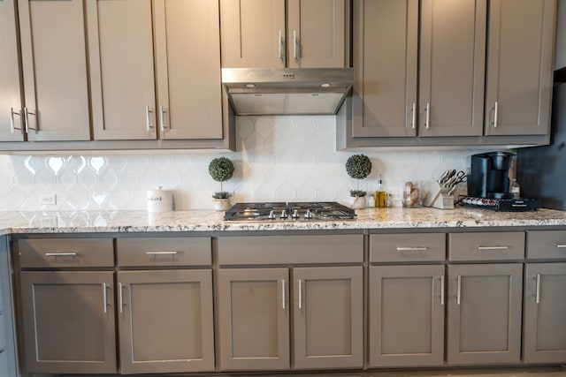 kitchen featuring stainless steel gas stovetop, tasteful backsplash, gray cabinets, and under cabinet range hood