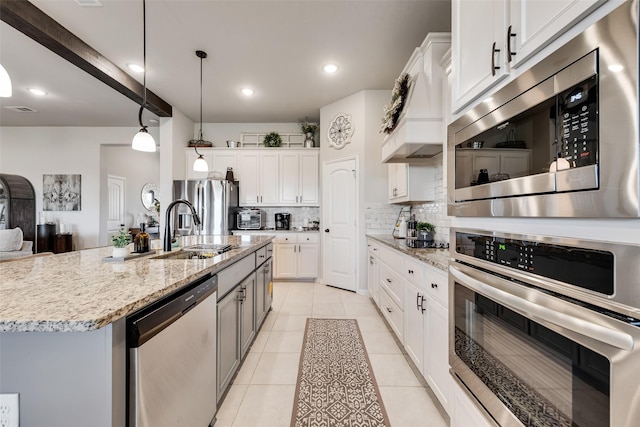 1016 Northern Oaks Ct, Springtown, TX 76082 - kitchen with appliances with stainless steel finishes, a sink, decorative backsplash, light stone countertops, and decorative light fixtures