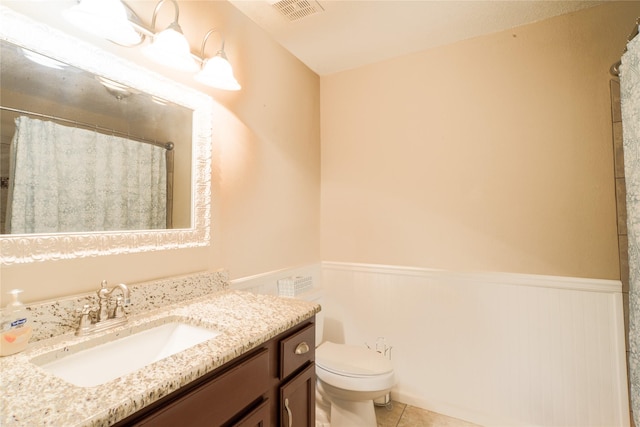 bathroom featuring tile patterned flooring, wainscoting, visible vents, and toilet