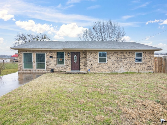 ranch-style home featuring a patio, brick siding, a front yard, and fence