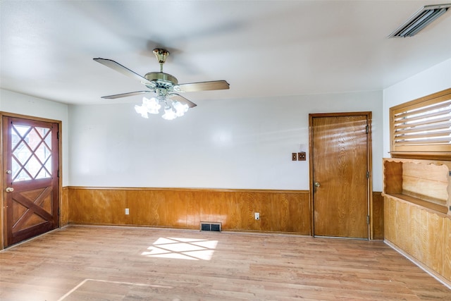 entryway with a wainscoted wall, light wood-style flooring, wooden walls, and visible vents