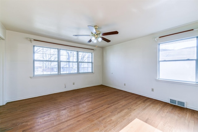 empty room with a healthy amount of sunlight, light wood-style floors, ceiling fan, and visible vents