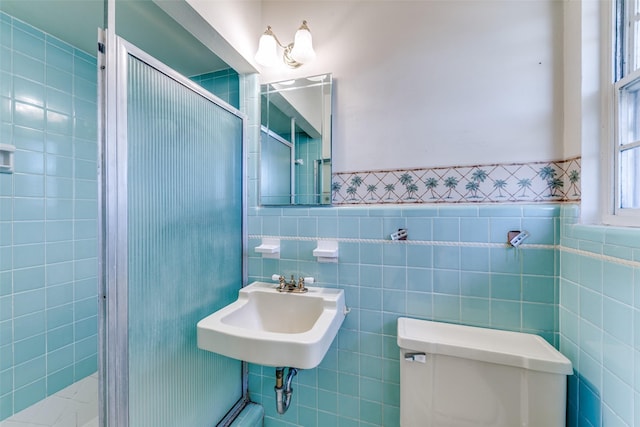 bathroom with a wainscoted wall, a sink, tile walls, and toilet