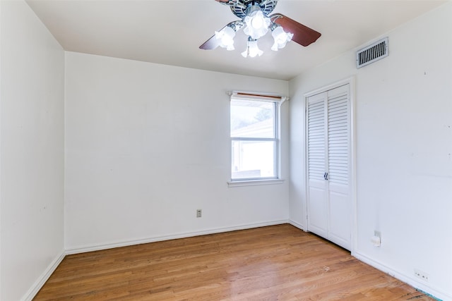 spare room with light wood-style floors, ceiling fan, visible vents, and baseboards