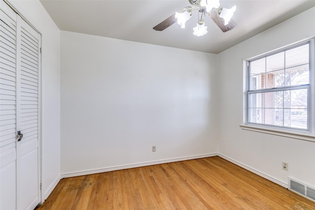 unfurnished bedroom featuring light wood finished floors, a closet, visible vents, a ceiling fan, and baseboards