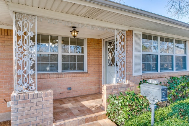 doorway to property with covered porch and brick siding