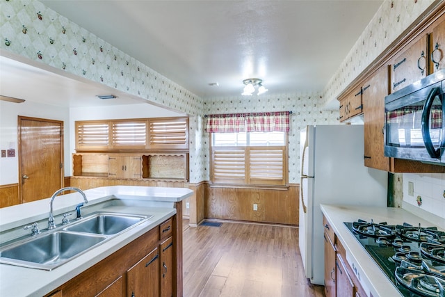 kitchen with light countertops, black gas stovetop, a sink, and wallpapered walls