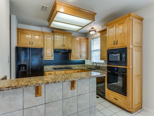 kitchen featuring visible vents, a breakfast bar, under cabinet range hood, black appliances, and a sink