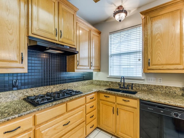 kitchen with light stone counters, under cabinet range hood, a sink, black appliances, and tasteful backsplash