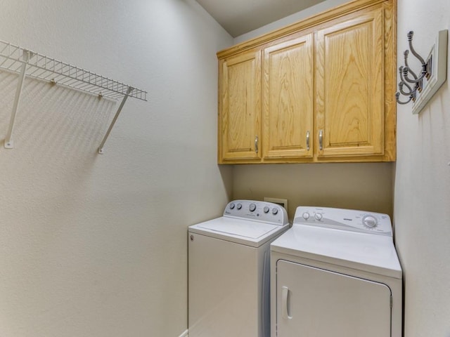 laundry room with washing machine and clothes dryer and cabinet space