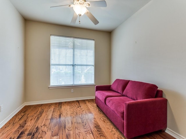 living area with ceiling fan, baseboards, and wood finished floors