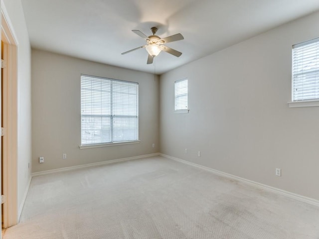 spare room with baseboards, ceiling fan, and light colored carpet