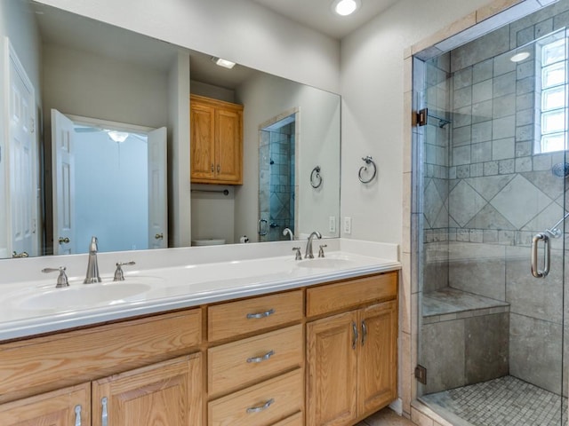 bathroom with double vanity, a sink, toilet, and a shower stall