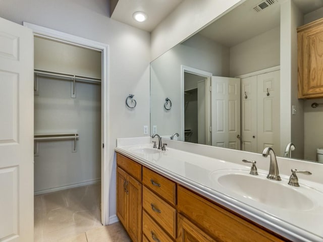 bathroom featuring visible vents, a sink, baseboards, and double vanity