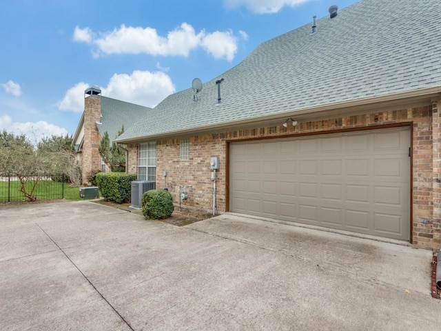 exterior space featuring brick siding, a shingled roof, concrete driveway, central AC unit, and a garage