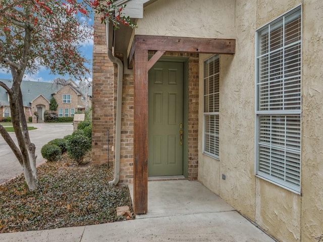 property entrance with brick siding and stucco siding