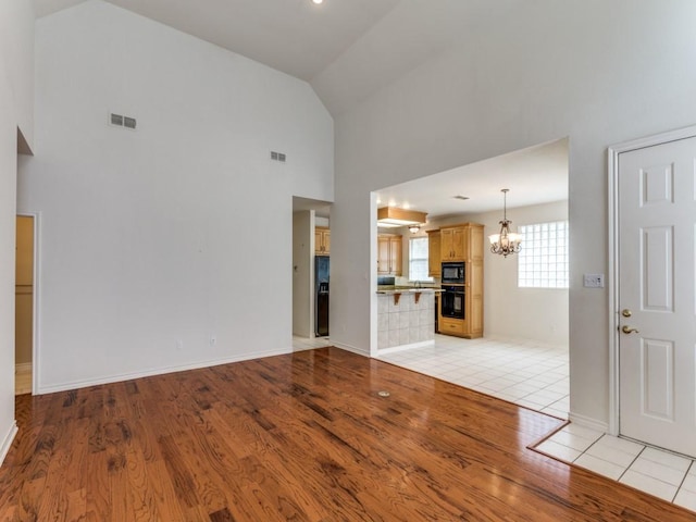 unfurnished living room featuring light wood-style floors, a chandelier, and visible vents