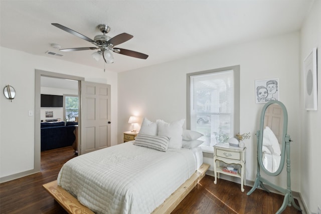 bedroom with a ceiling fan, wood finished floors, visible vents, and baseboards