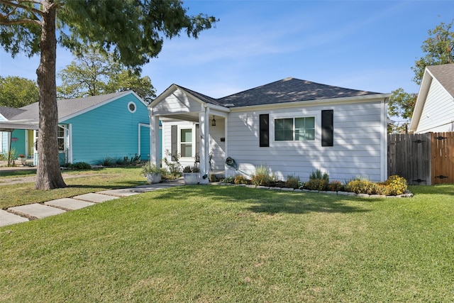 view of front of home featuring a shingled roof, fence, and a front lawn