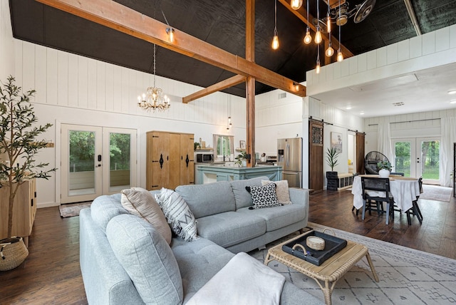 living room with french doors, beam ceiling, dark wood finished floors, a high ceiling, and a barn door