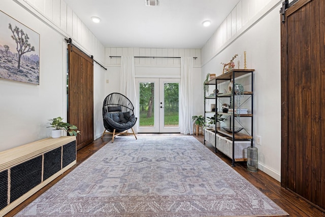 sitting room featuring dark wood-type flooring, french doors, visible vents, and a barn door