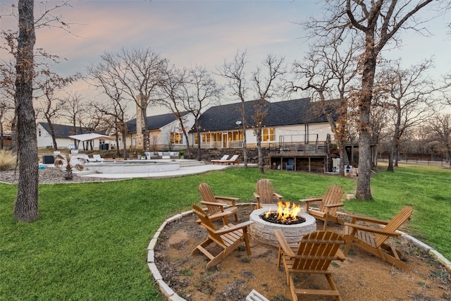 rear view of house with a fenced in pool, a yard, an outdoor fire pit, a patio area, and a wooden deck