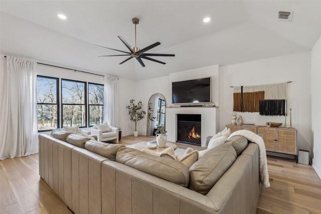 living area featuring recessed lighting, visible vents, light wood-style flooring, a ceiling fan, and a warm lit fireplace