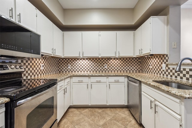 kitchen featuring appliances with stainless steel finishes, backsplash, a sink, and white cabinetry