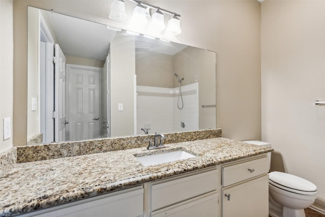 bathroom featuring tiled shower, vanity, and toilet