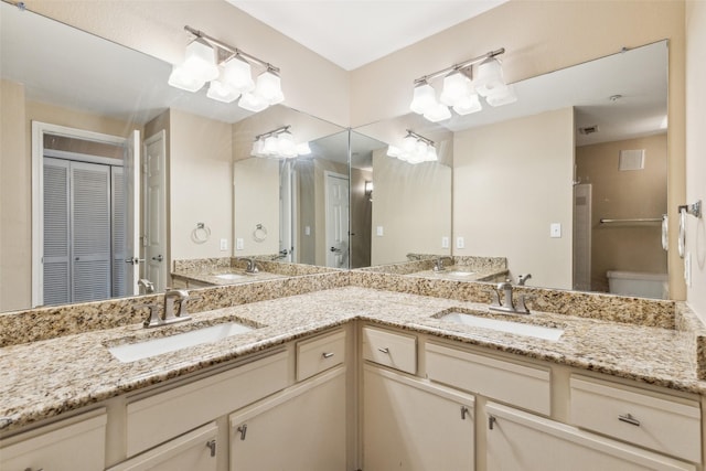 full bath with a closet, a sink, toilet, and double vanity