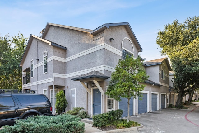 view of front of property with a garage, concrete driveway, and stucco siding