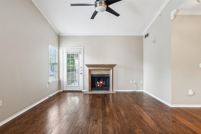 unfurnished living room with a warm lit fireplace, hardwood / wood-style flooring, a ceiling fan, baseboards, and crown molding