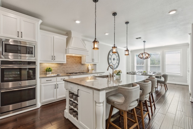 kitchen featuring premium range hood, a sink, tasteful backsplash, stainless steel appliances, and crown molding