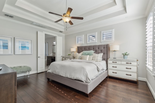 bedroom with a tray ceiling, visible vents, and dark wood-style flooring