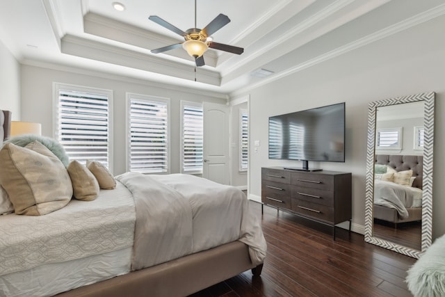 bedroom with visible vents, baseboards, a tray ceiling, ornamental molding, and dark wood-style flooring