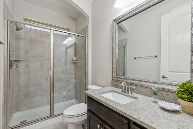 full bathroom featuring a stall shower, toilet, and vanity