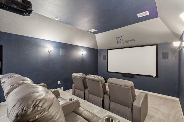 carpeted home theater with a textured wall, visible vents, baseboards, and vaulted ceiling